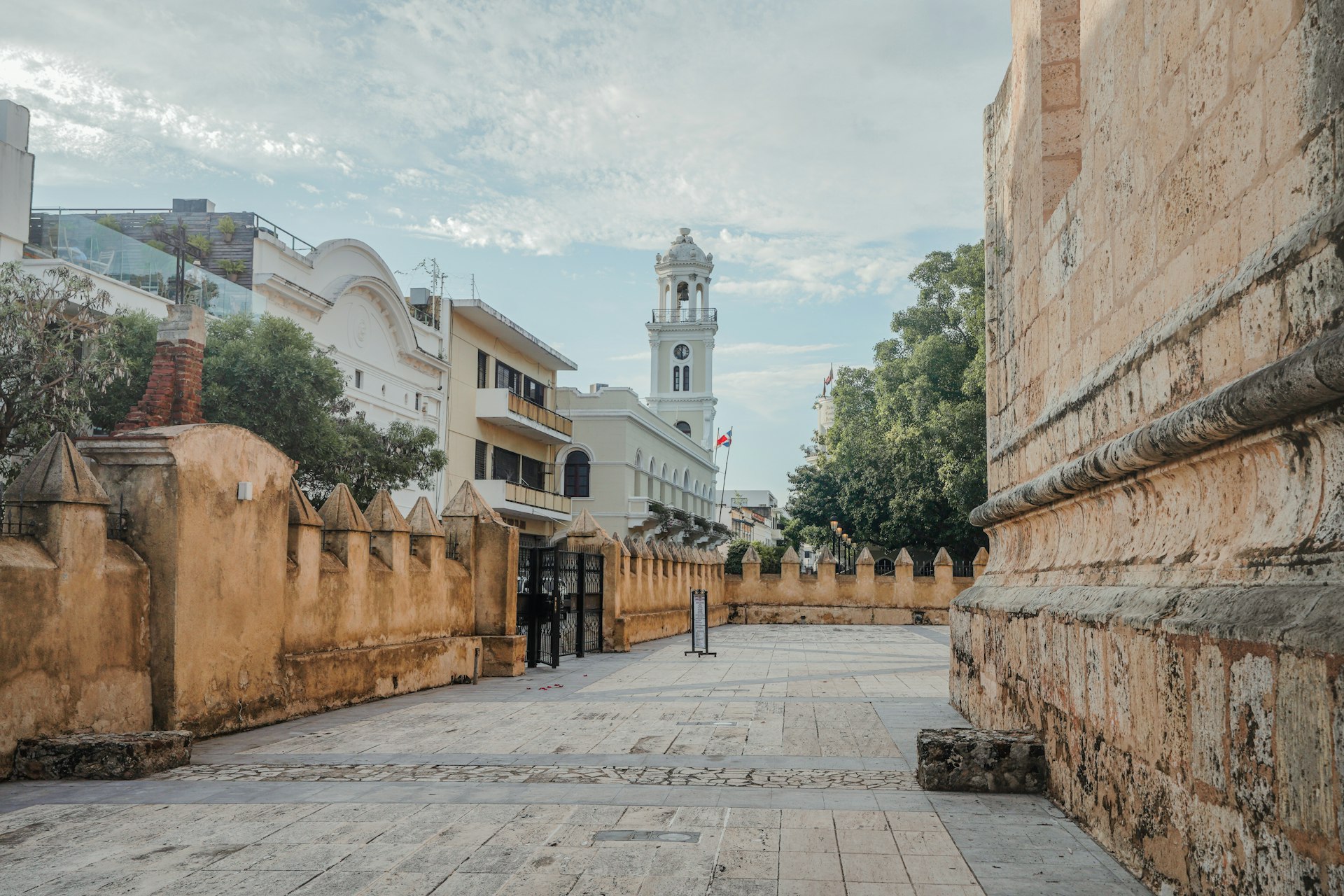 a narrow street with a clock tower in the background